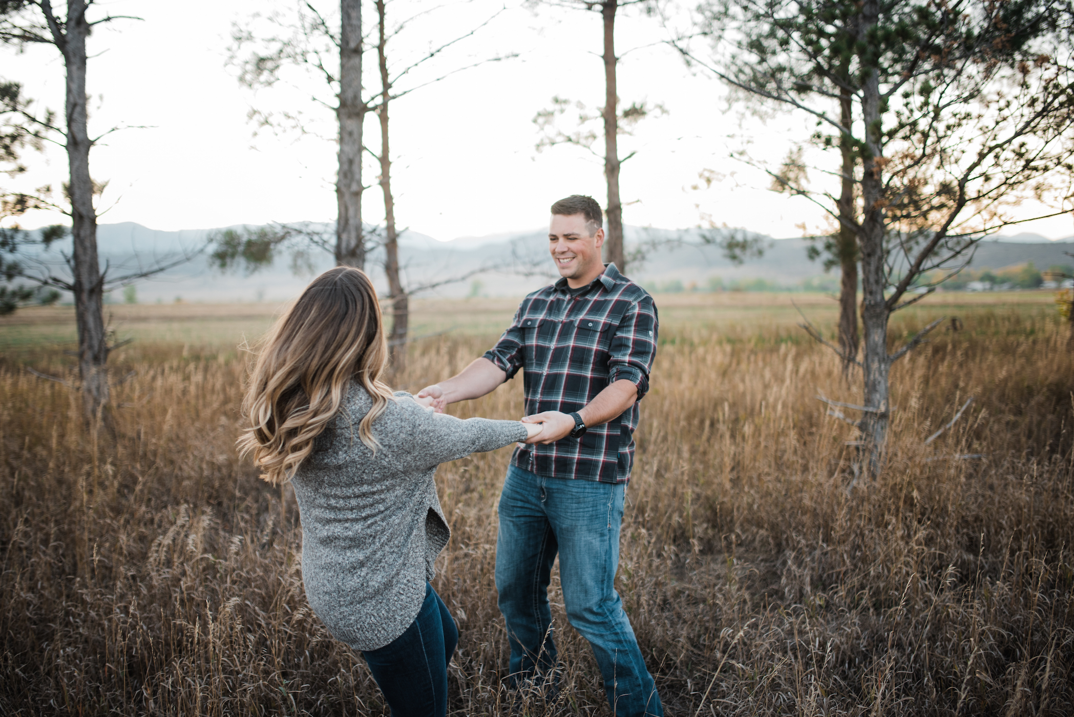 Couples lifestyle photoshoot holding hands spinning in Fort Collins field