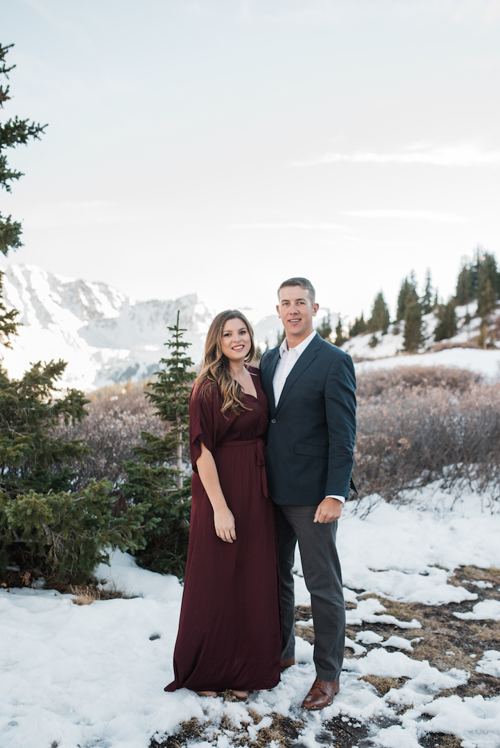 Taylor and Chris smiling with pine trees and mountains in background