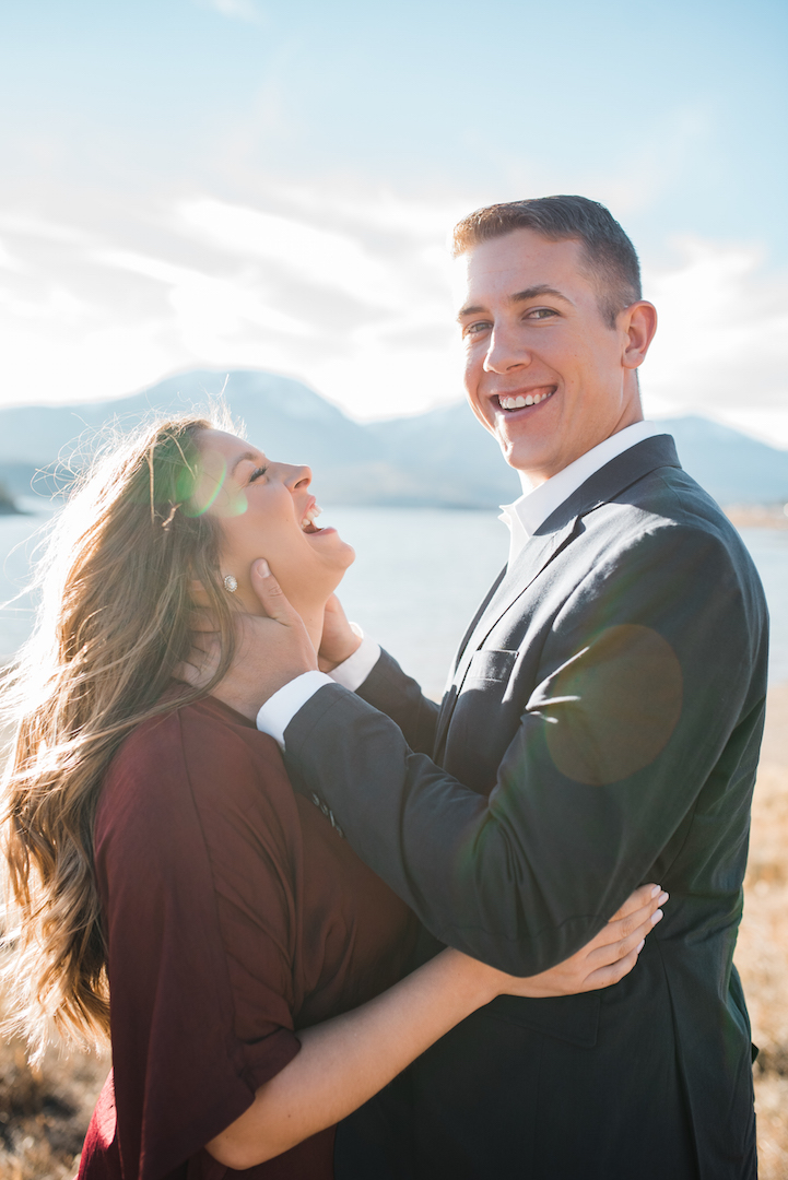 Chris and Taylor laughing in front of Lake Dillon with sun rays shining through 