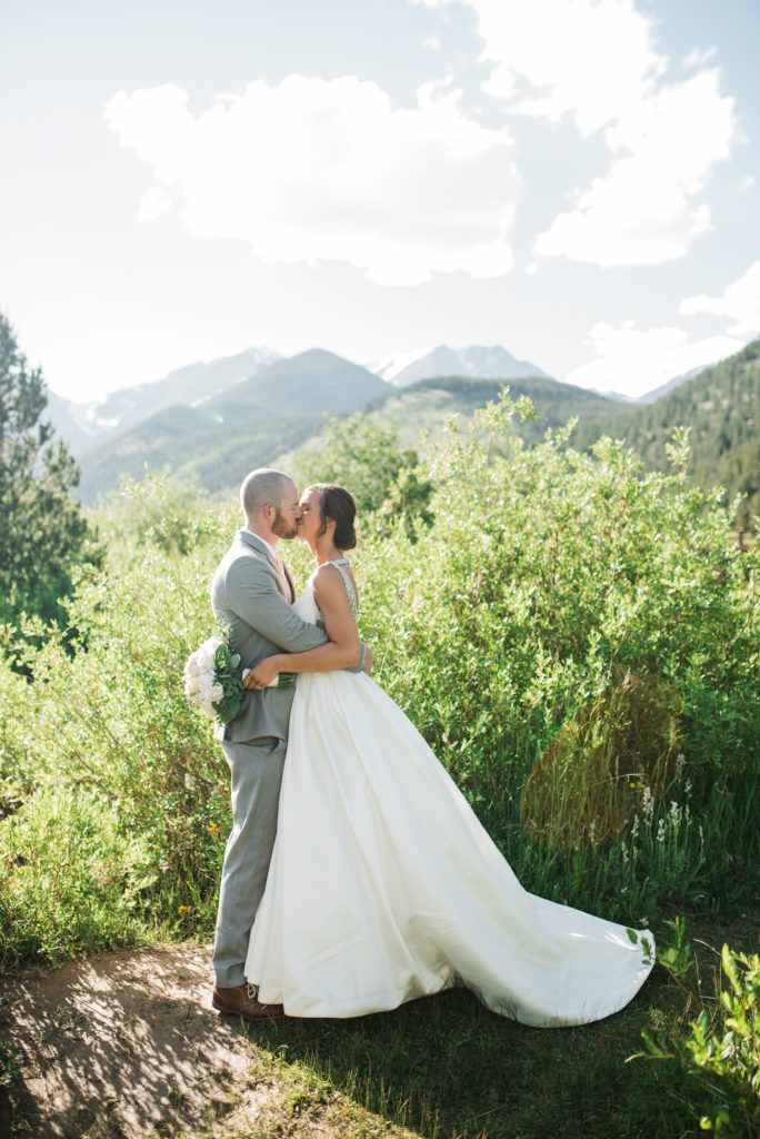 Kristine and Drew kissing with mountains behind them at Estes Park wedding 