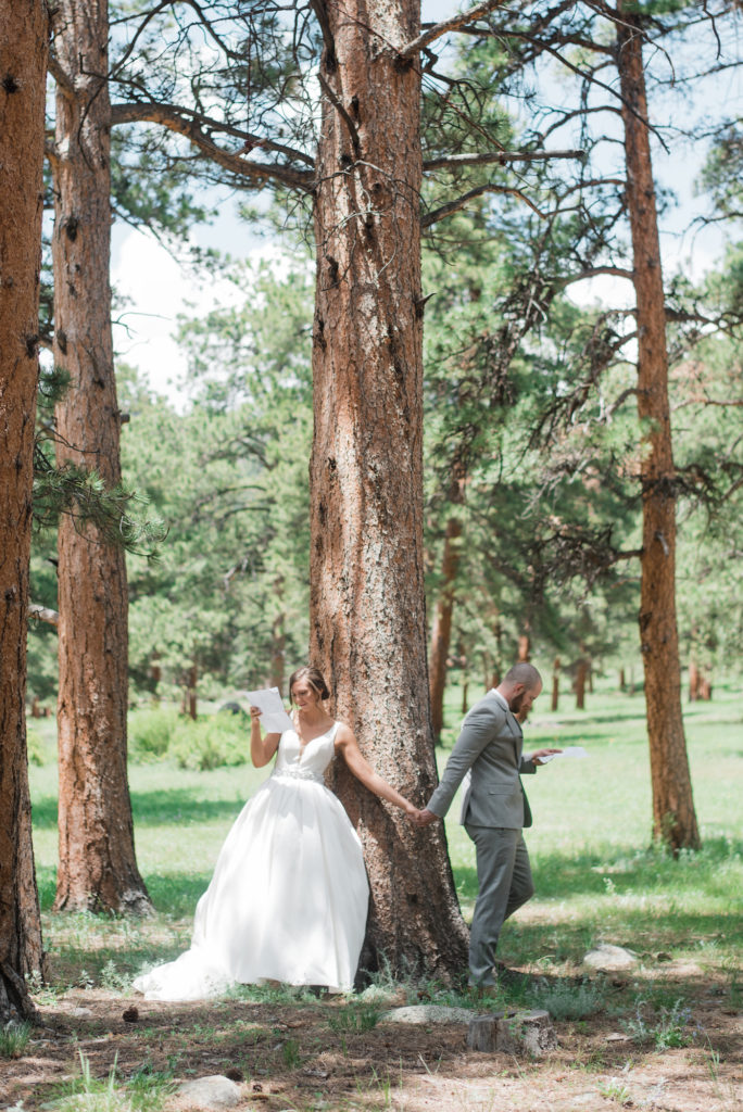 Kristine and Drew holding hands at tree before ceremony at Estes Park wedding 