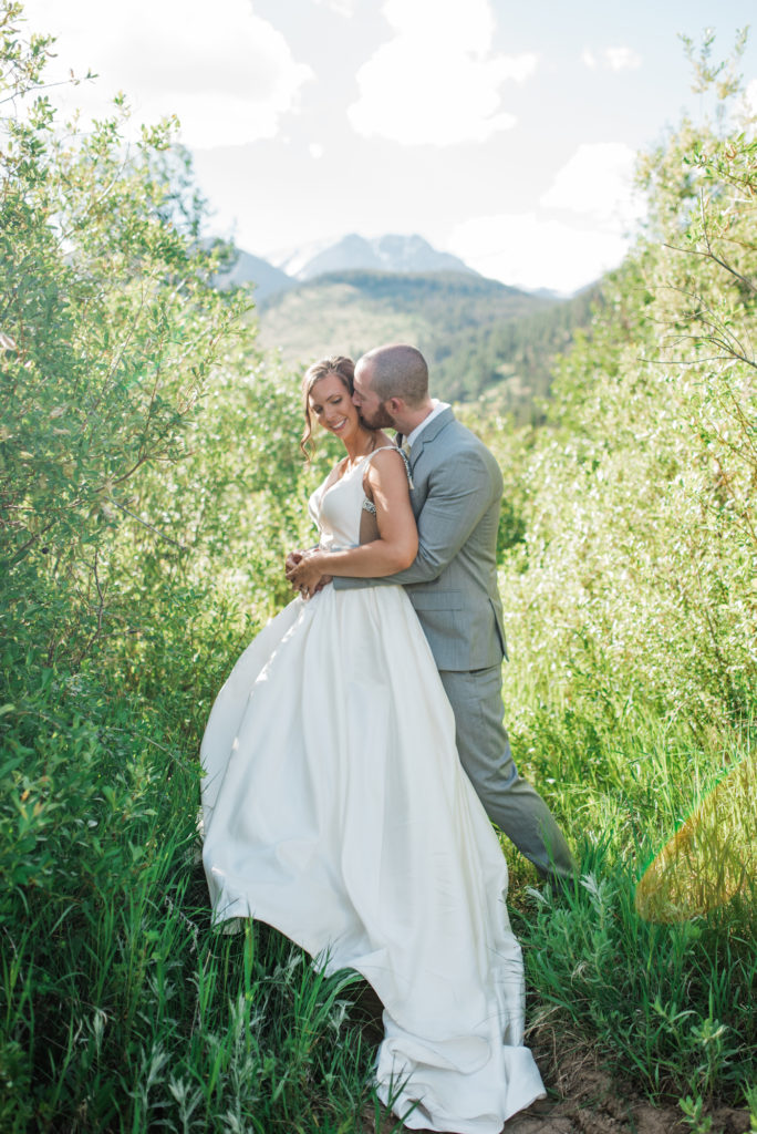 Kristine and Drew hugging with mountains behind them at Estes Park wedding 