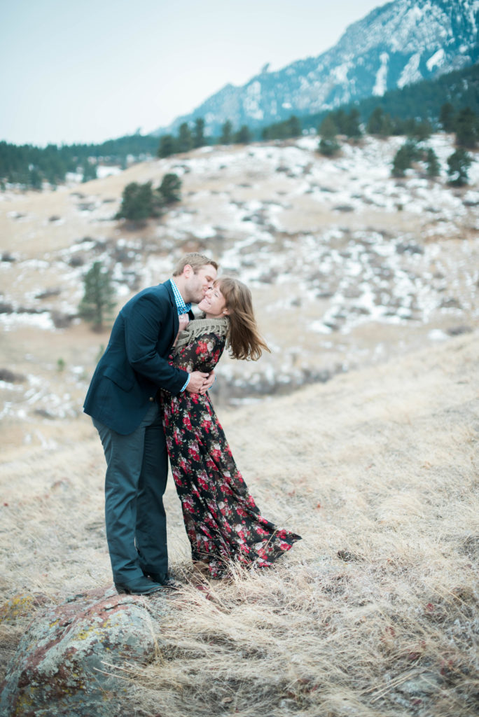 winter engagement photoshoot couple kissing in front of boulder foothills