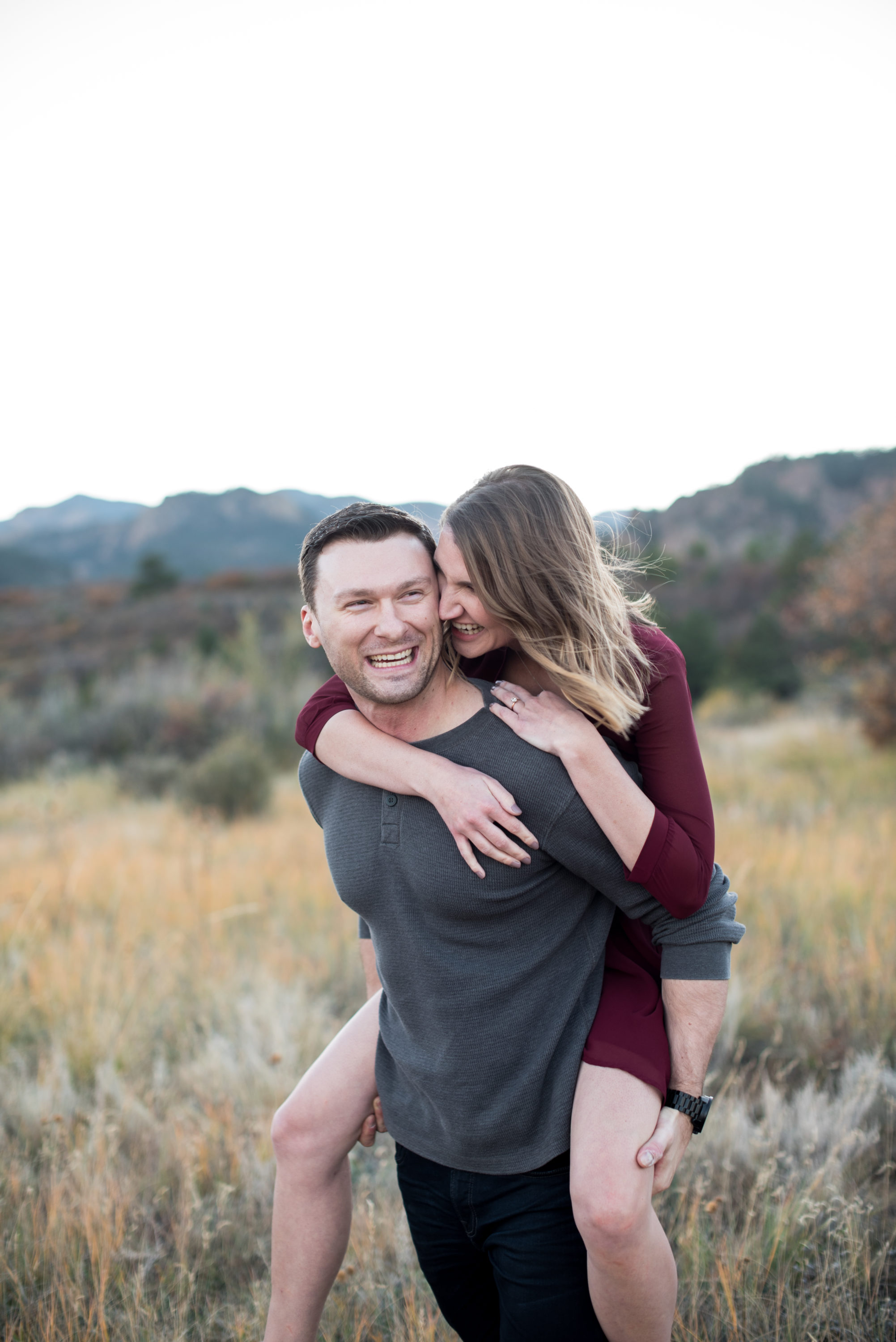 colorado springs engagement photos piggy back in sunny meadow