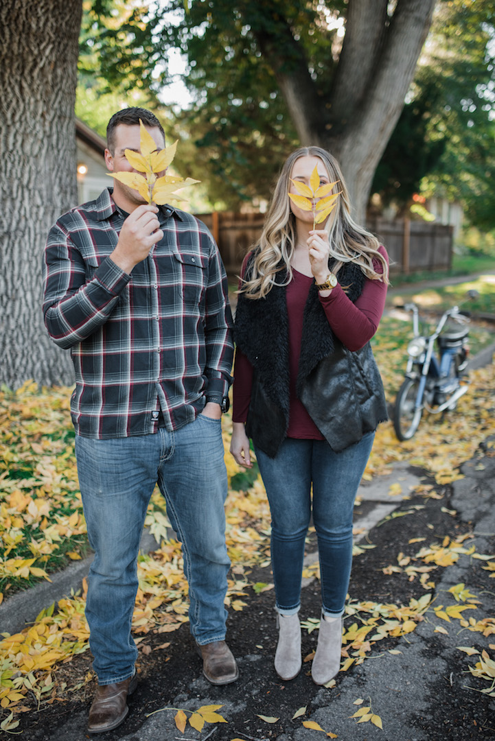 Max and Jenae holding big yellow leaves in front of their faces
