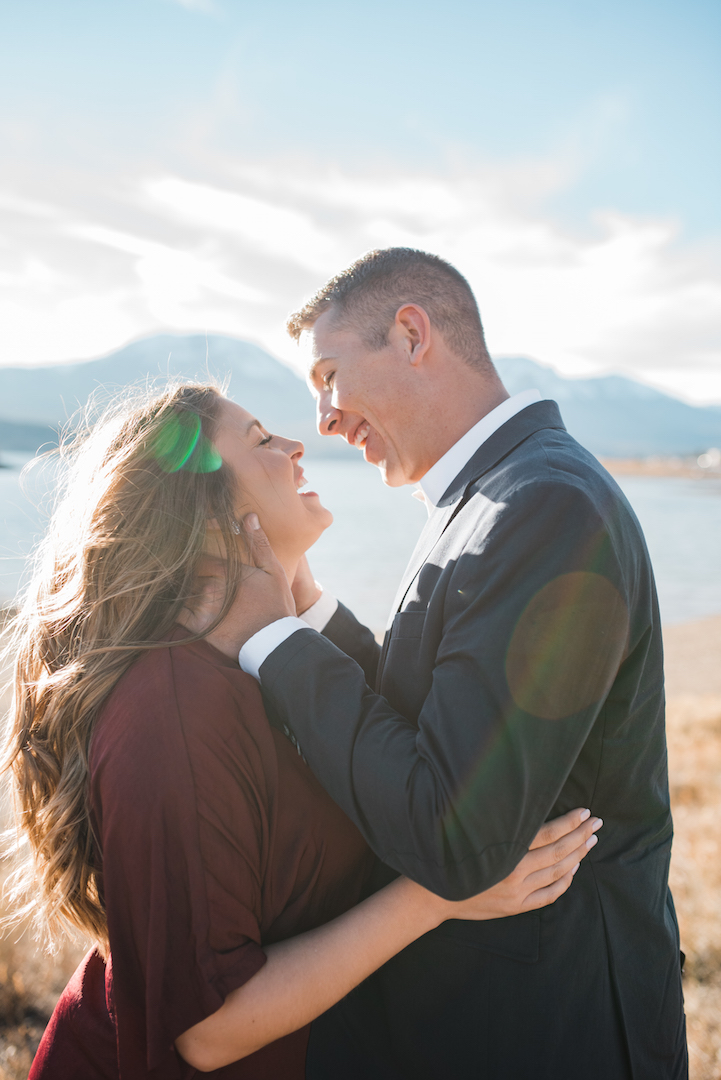 Chris kissing Taylor in front of Lake Dillon with sun rays shining through 