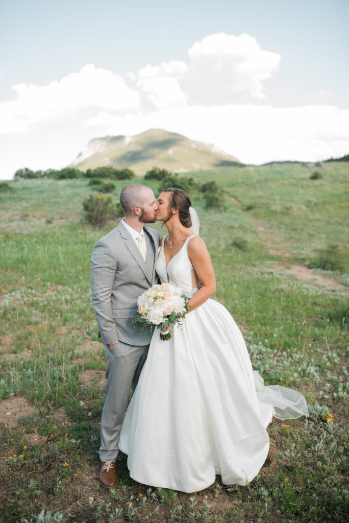 Drew and Kristine kissing at Estes Park Wedding with mountains