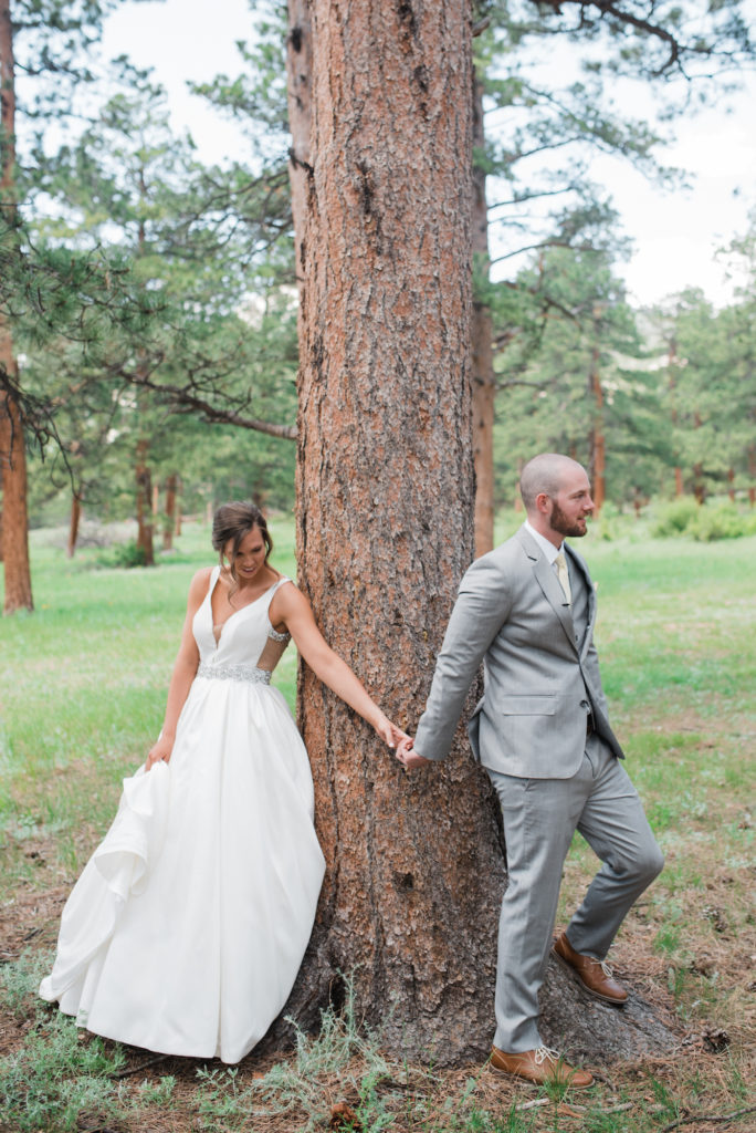 Kristine and Drew holding hands at tree before ceremony at Estes Park wedding 