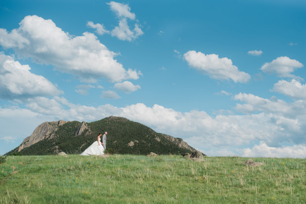 Kristine and Drew walking with mountains behind them at Estes Park wedding 