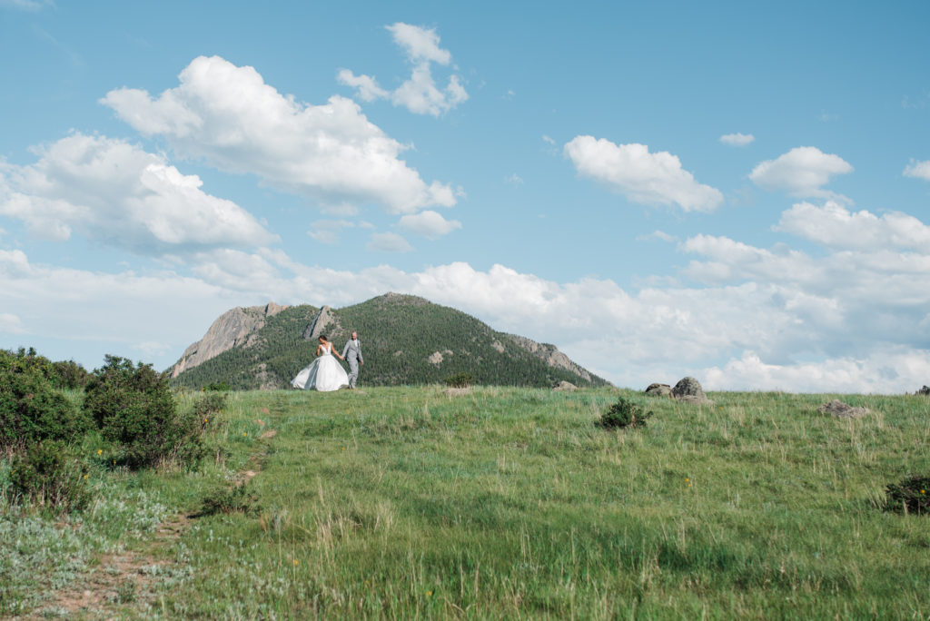 Kristine and Drew walking with mountains behind them at Estes Park wedding 