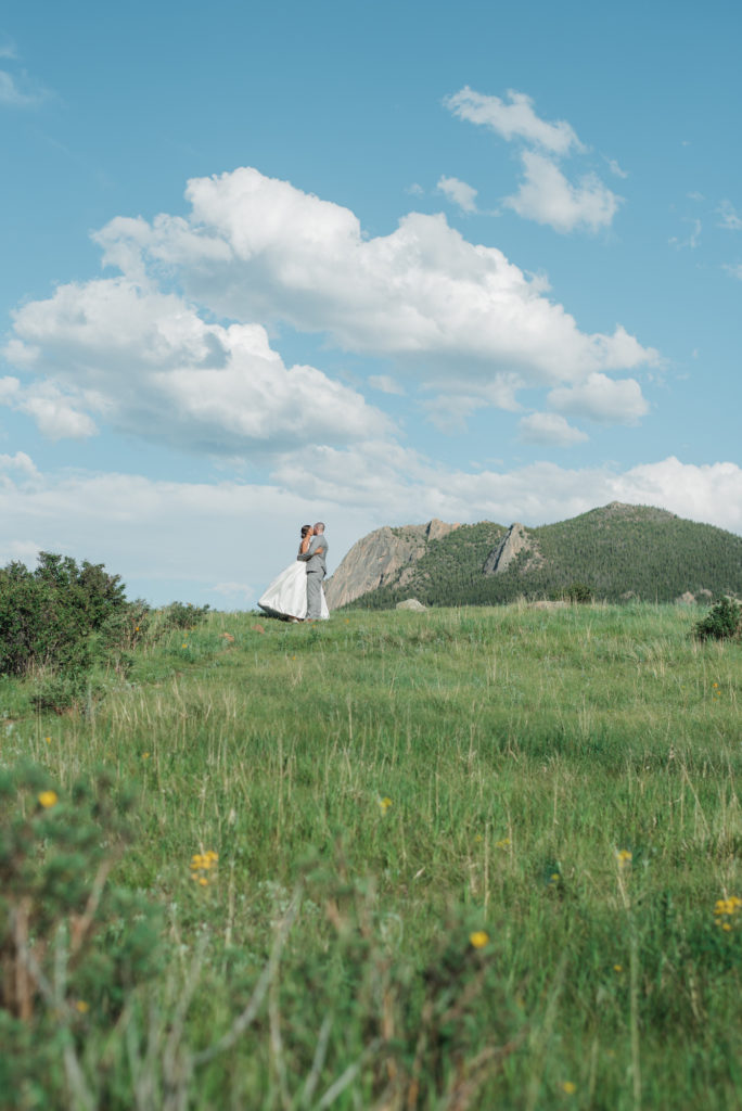 Kristine and Drew kissing with mountains behind them at Estes Park wedding 
